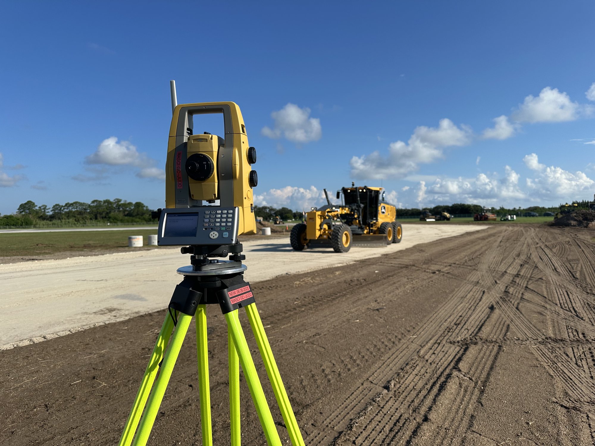 Robotic total station calibrated on subgrade with motor grader working in the background
